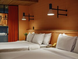 Una habitación de hotel con dos camas, cabecero de madera y lámparas colgantes.