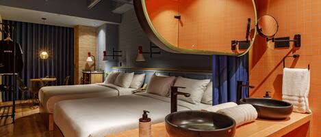 A modern hotel room with a large bed, a wooden ceiling, and a bathroom with a large mirror and two bowls on the sink.