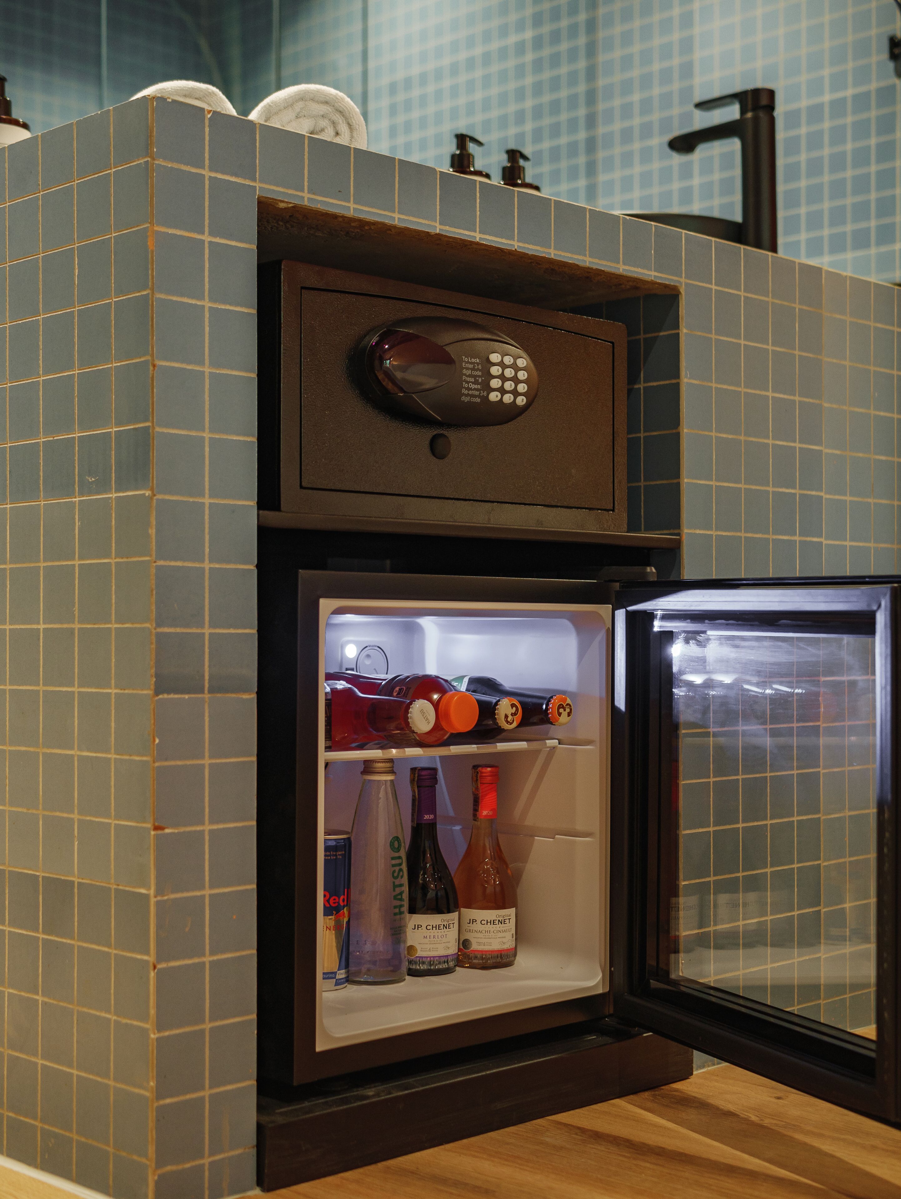 Un petit réfrigérateur doté d’un verrouillage numérique et contenant diverses bouteilles de boissons.