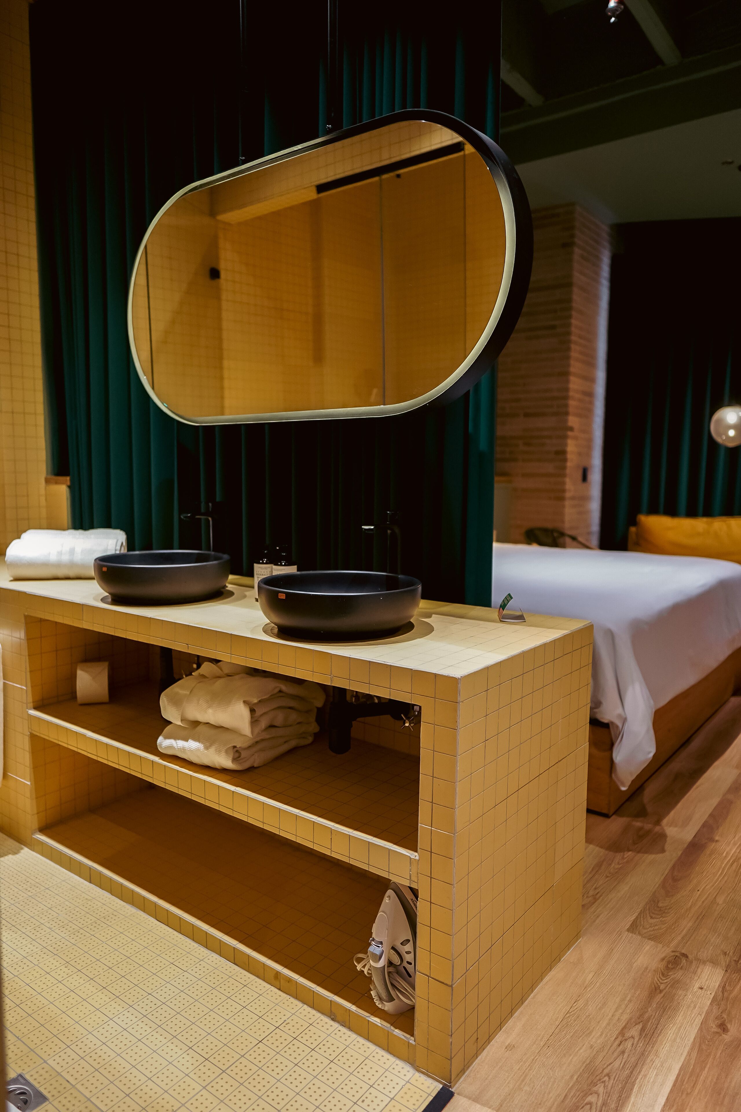 A bathroom with a wooden vanity, two sinks, a mirror, and a towel rack.