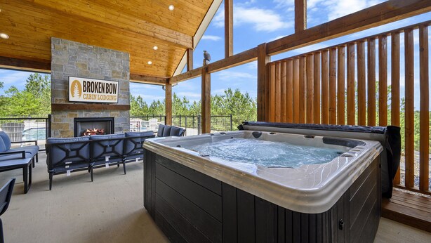 Eine Hütte mit Kamin aus Stein, Whirlpool und Sitzgelegenheit im Freien.