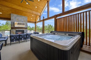 Eine Hütte mit Kamin aus Stein, Whirlpool und Sitzgelegenheit im Freien.