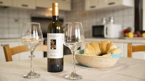A bottle of wine, two glasses, and a basket of bread on a table. - Dependance Via Deffenu a 100 metri dalla spiaggia (Tortoli')