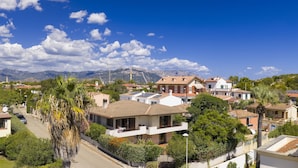 A residential area with houses, solar panels, and a mountainous backdrop. - Dependance Via Deffenu a 100 metri dalla spiaggia (Tortoli')