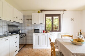 Een koelkast, een oven, kookgerei, borden en bestek, een eettafel