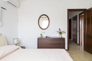 Un dormitorio con cama, cómoda, espejo y pasillo que conduce a una puerta.