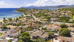 Une zone résidentielle côtière, avec des maisons, une plage et une chaîne de montagnes en arrière-plan.