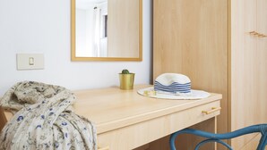 A room with a wooden desk, a mirror, a hat, a small plant, and a blue chair. - Dependance Via Deffenu a 100 metri dalla spiaggia (Tortoli')