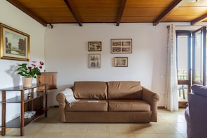 Una sala de estar con un sofá marrón, un mueble de entretenimiento de madera y cuadros en la pared.