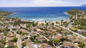 Une ville côtière aux maisons aux toits de tuiles rouges, avec une plage et une vue dégagée sur l’océan.