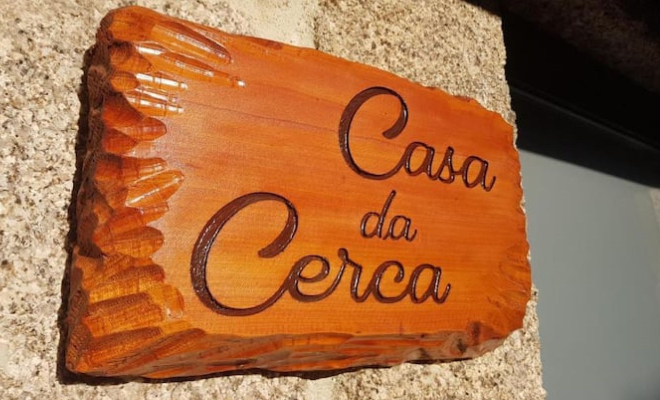Ein hölzernes Schild mit der eingravierten Aufschrift 'Casa da Cerca'.