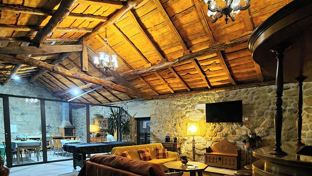 A cozy interior with a wooden ceiling, a sofa, a table, and a bar area.