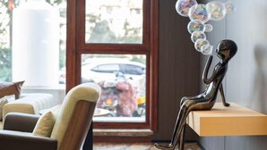 A modern interior with a sofa, a decorative sculpture, and a view through a window. - Chonpines Hetel (Qingdao Jimo Hetel) (Qingdao)