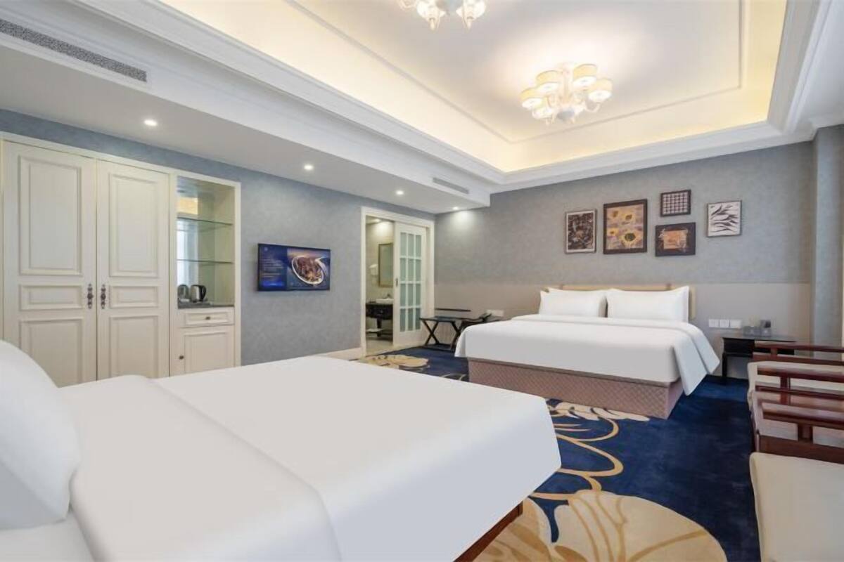 A hotel room with two beds, a desk, a chair, and a wardrobe.