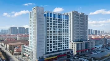 A high-rise hotel with multiple floors, a parking area in front, and a clear view of the surrounding cityscape.