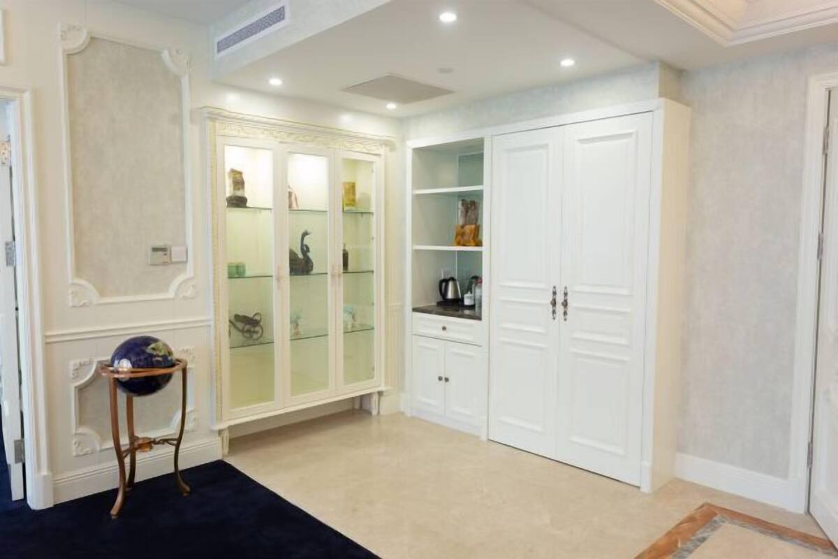 A room with a white wardrobe, a glass display cabinet, and a small round table with a globe.