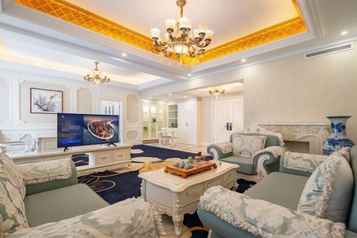 A spacious living room with a television, sofas, a coffee table, and a chandelier.