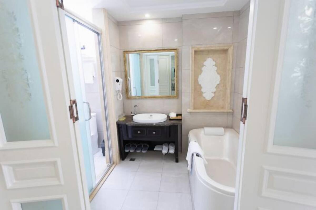 A bathroom with a white sink, a mirror, a bathtub, and a vanity with a mirror.