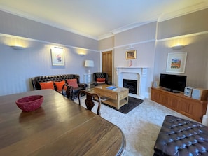 Relax in this stylish living room with a large dining table, comfortable sofa, and fireplace.