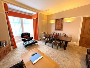 A room with a dining table, chairs, a sofa, and a coffee table.