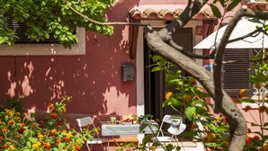 Eine Terrasse mit Tisch für zwei Personen, umgeben von Stühlen, einem Ziegeldach und einer roten Wand.