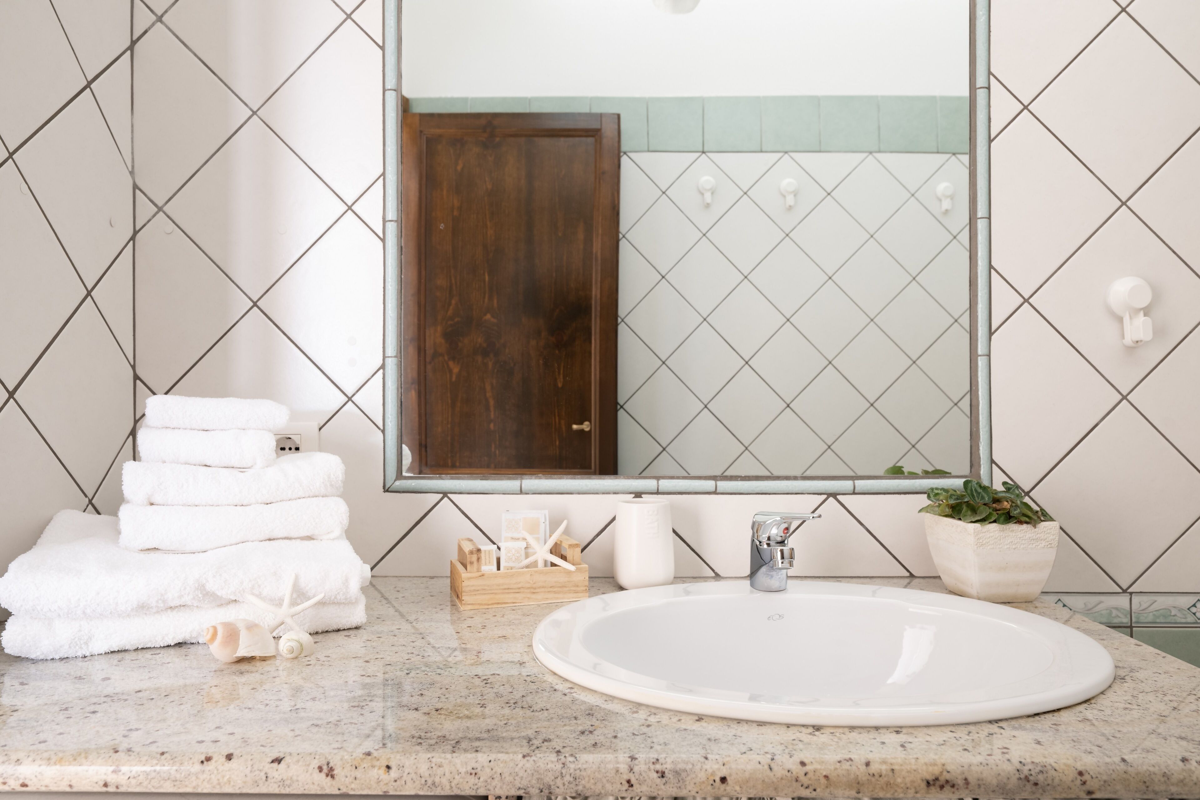 A bathroom with a large mirror, a sink, and a stack of white towels.