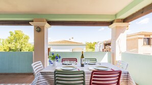 An outdoor patio with a table set for four, surrounded by chairs, and a view of a residential area in the background. - Il GECO Holiday Home (Tortoli')