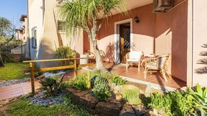 A building with a patio area, outdoor furniture, and a variety of plants. - Vacation House Summer By The Sea (Tortoli')