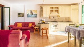 A cozy living room with a red sofa and a dining area with a table and chairs. - Vacation House Summer By The Sea (Tortoli')