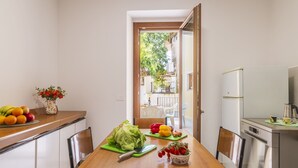 A compact kitchen with a wooden table, a refrigerator, and a view of the outside. - Casa Sulis Holiday Home (Tortoli')