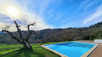 Una piscina con una vista despejada del paisaje circundante, que incluye un árbol y colinas al lejano.