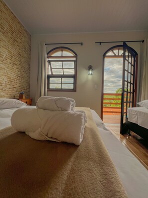 Una habitación de hotel con dos camas, un ventanal grande y vistas al exterior.