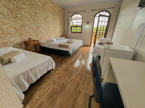 Une chambre d’hôtel avec deux lits, un plancher en bois, un mur en briques et une vue à travers des fenêtres en arc de cercle.