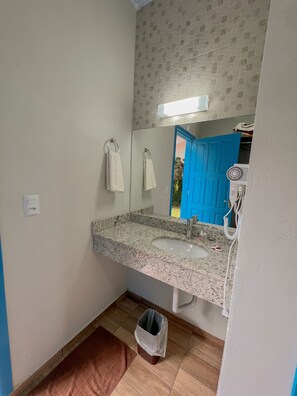 Une salle de bain avec un lavabo doté d’un plan de travail en granit, un miroir, une porte bleue et un porte-serviettes blanc.