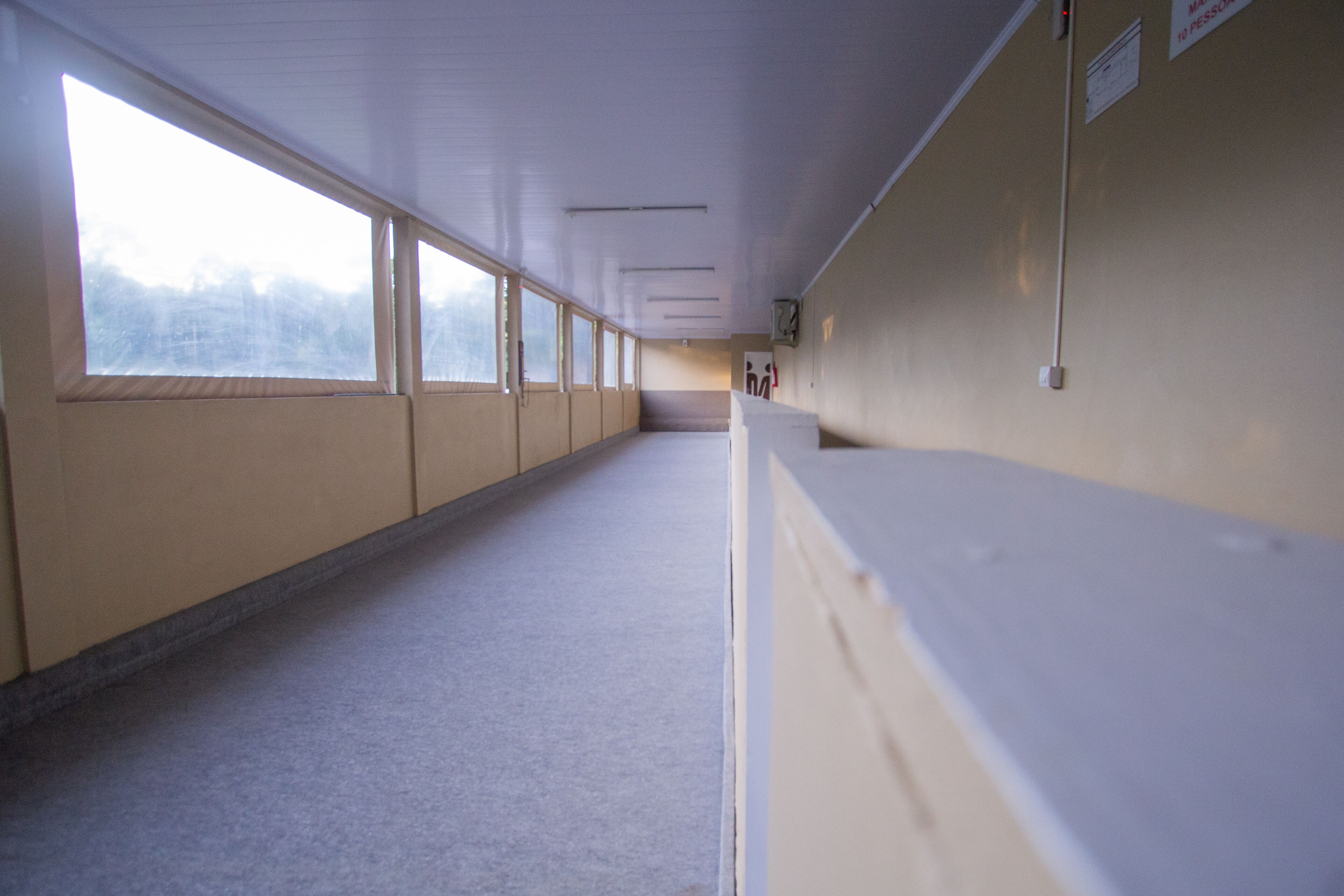 A long, narrow hallway with large windows on one side and a white counter on the other.