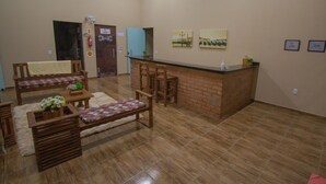 A spacious living area with a wooden bench, a small table with a plant, and a brick counter.