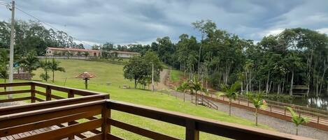 A wooden deck with a view of a grassy area, a pathway, and trees.