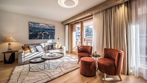 Un salon moderne avec un canapé, deux fauteuils, une table basse et un tableau accroché au mur.