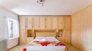 Une chambre à coucher avec un lit en bois, une armoire intégrée, des tables de chevet et un radiateur.