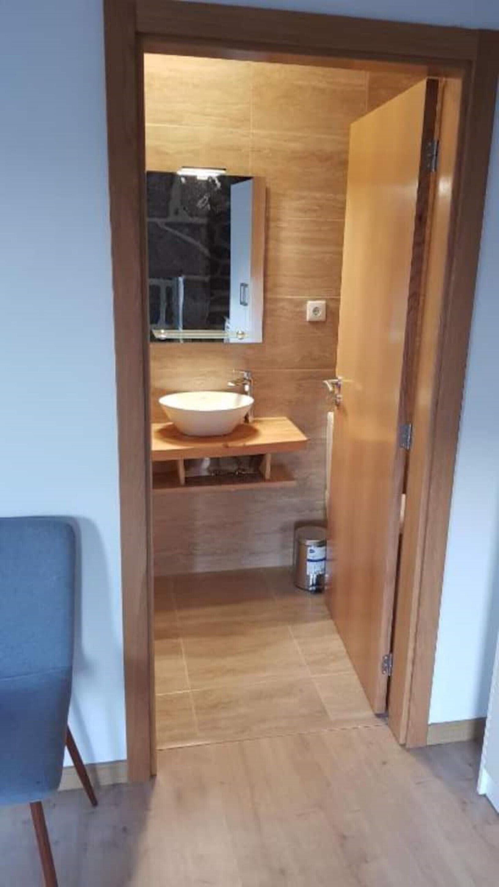 Une salle de bain moderne avec un grand lavabo blanc, un meuble-lavabo en bois et un miroir.