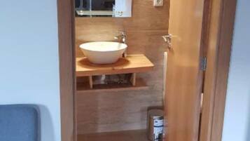 Une salle de bain moderne avec un grand lavabo blanc, un meuble-lavabo en bois et un miroir.