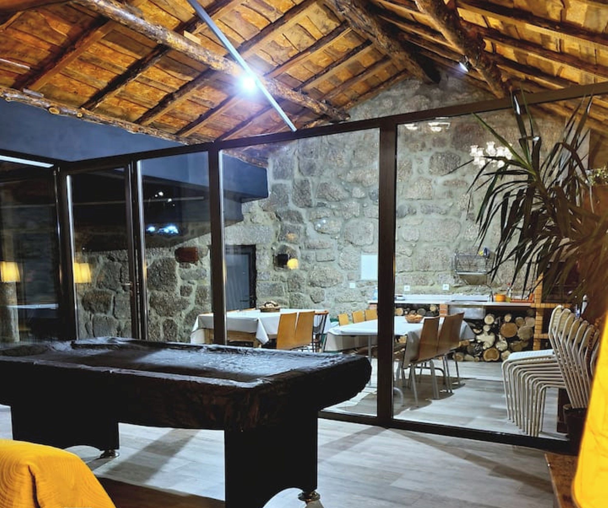 Una mesa de billar en una habitación con pared de piedra y techo de paja.