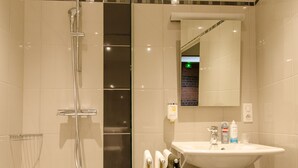 Un baño moderno con ducha de vidrio, un lavabo blanco y un espejo encima.