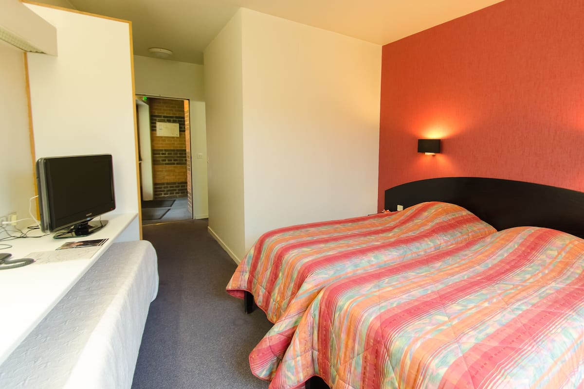 A hotel room with a bed, a desk with a computer, and a television.