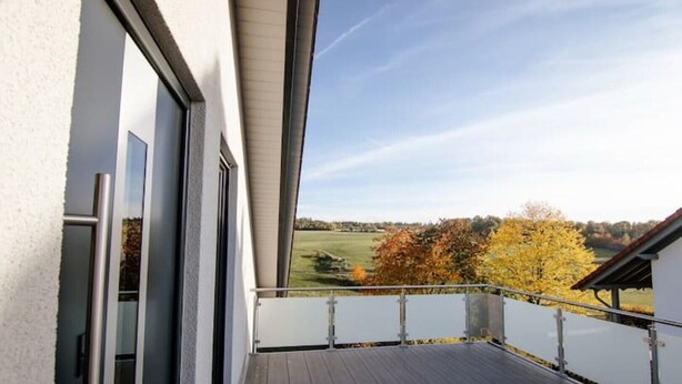 A balcony with a view of a grassy field and autumn trees. - Modern and bright vacation apartment with Hutewald view (Vöhl)