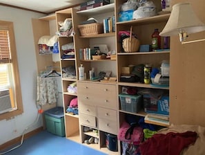A room with a large wardrobe, a small table, and a window with blinds.