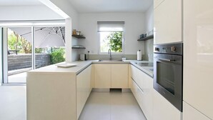 Eine moderne Küche mit einer großen Kochinsel, Backofen und Blick auf Grünflächen.