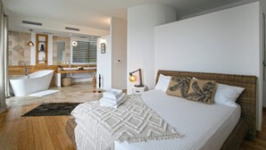 Een moderne hotelkamer met een groot bed, een eigen badkamer en uitzicht op de stad.