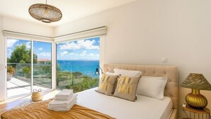 Un dormitorio con una cama grande, vista al mar y un balcón.