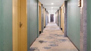 A hotel hallway with a marble-patterned carpet, green walls, and doors on both sides. - Ruining Hotel ( Xiangyang Gucheng North Street Branch) (Xiangyang)